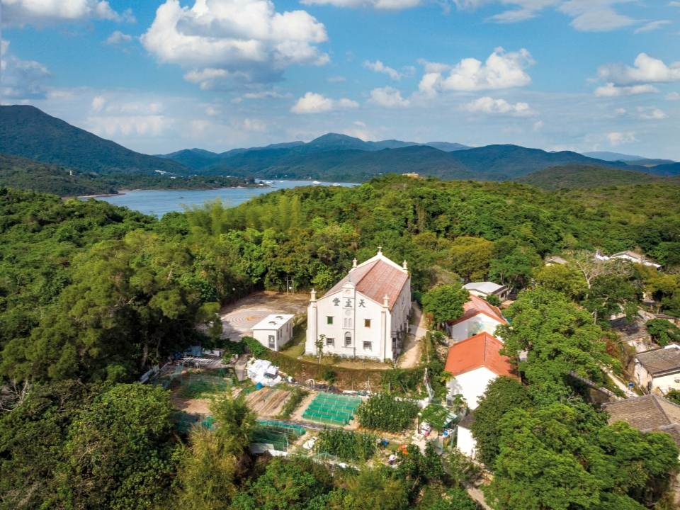 Aerial view looking down at St Joseph’s Chapel amid green trees and blue skies.