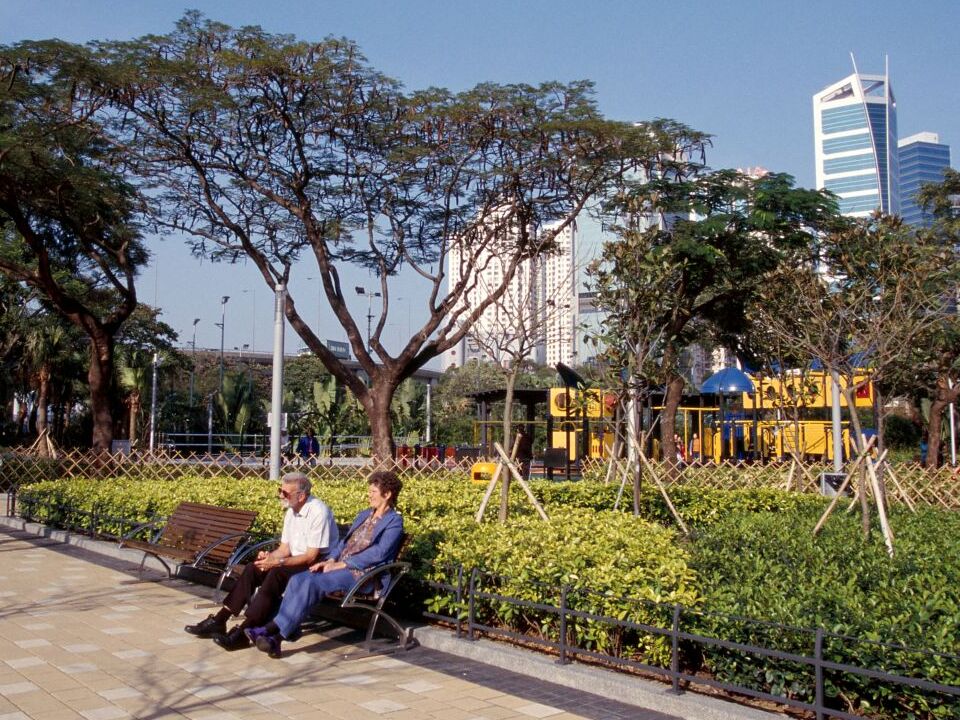 A couple seated at the benches amid the trees inside Victoria Park.