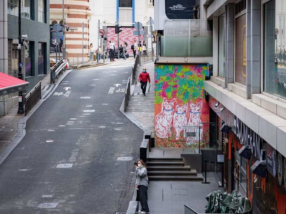 Looking up Wyndham Street with a street art mural of cats by DD Yung on a small red wall. 