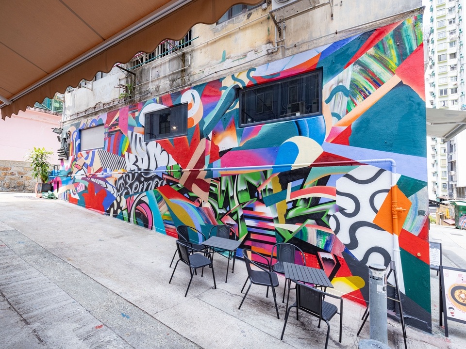Looking down a street with a colourful mural on Tai Ping Shan Street by Miguel Emerico. 