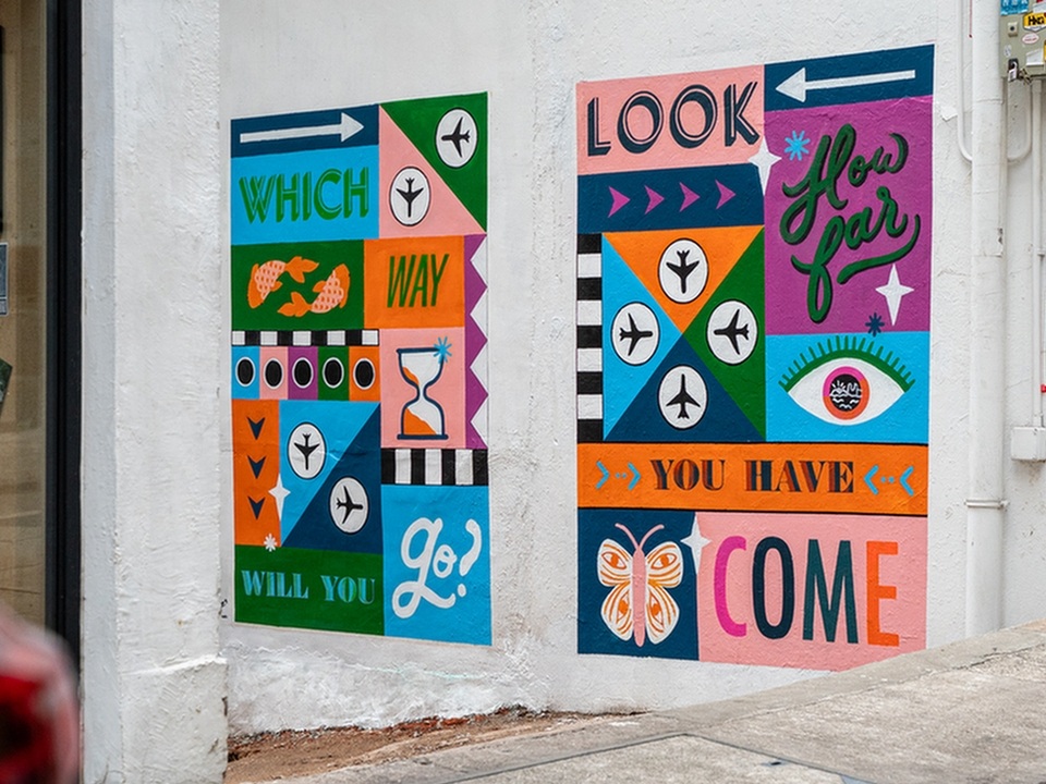 Two colourful street art paintings on a white wall by Erin Hung. 