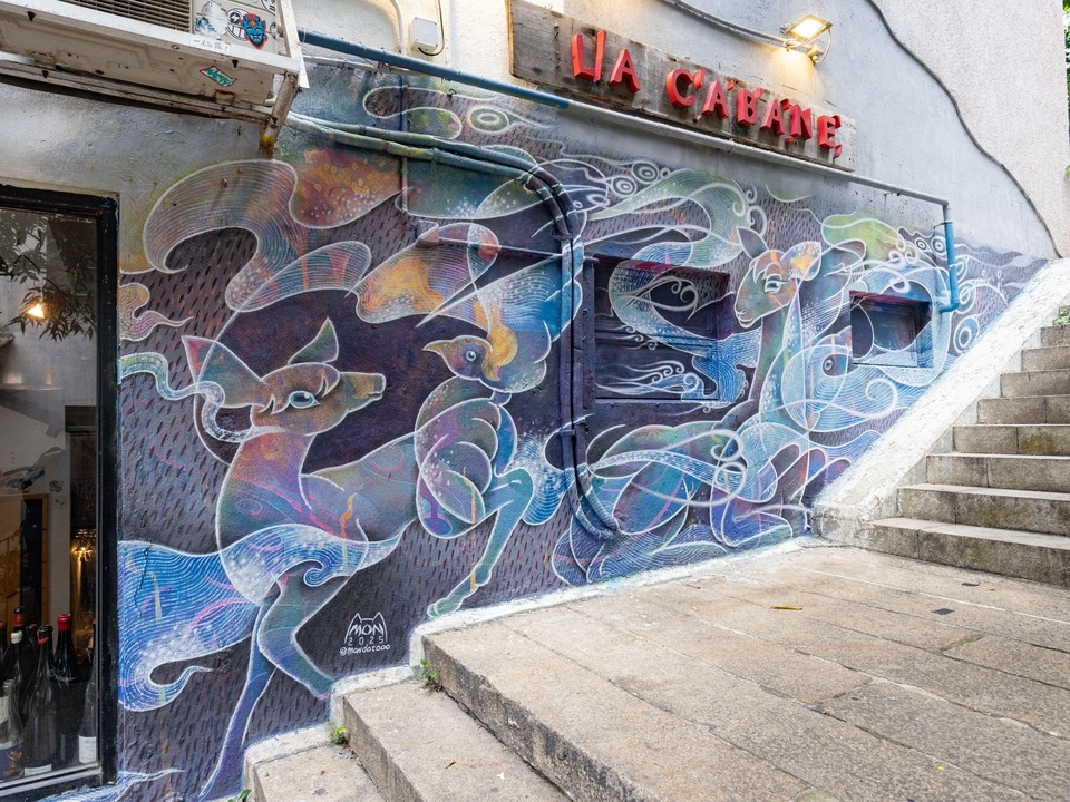 Street art mural by Mon with blue and purple on Shin Hing Street. 