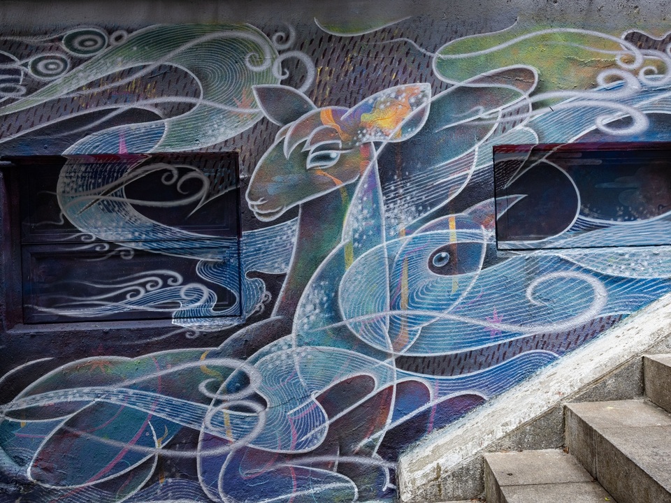 Close up of the art mural by Mon with blue and purple swirls depicting nature. 