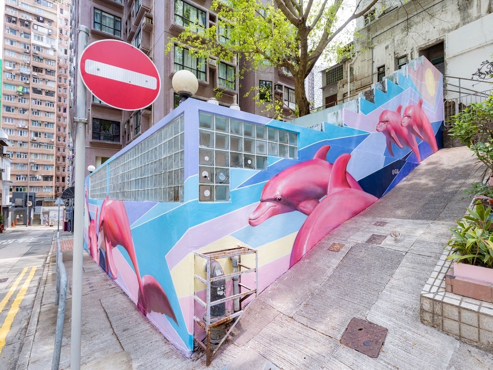 A street corner with a mural of pink dolphins by XEVA on Square Street. 