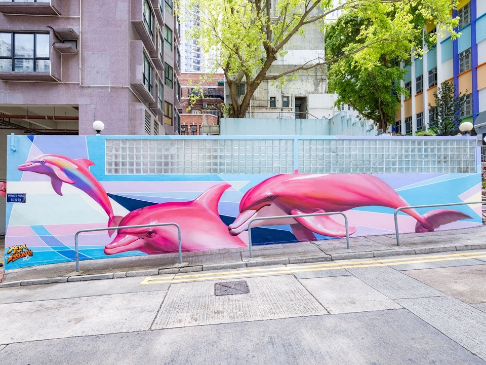 Square Street with a long mural with pink dolphins by XEVA. 