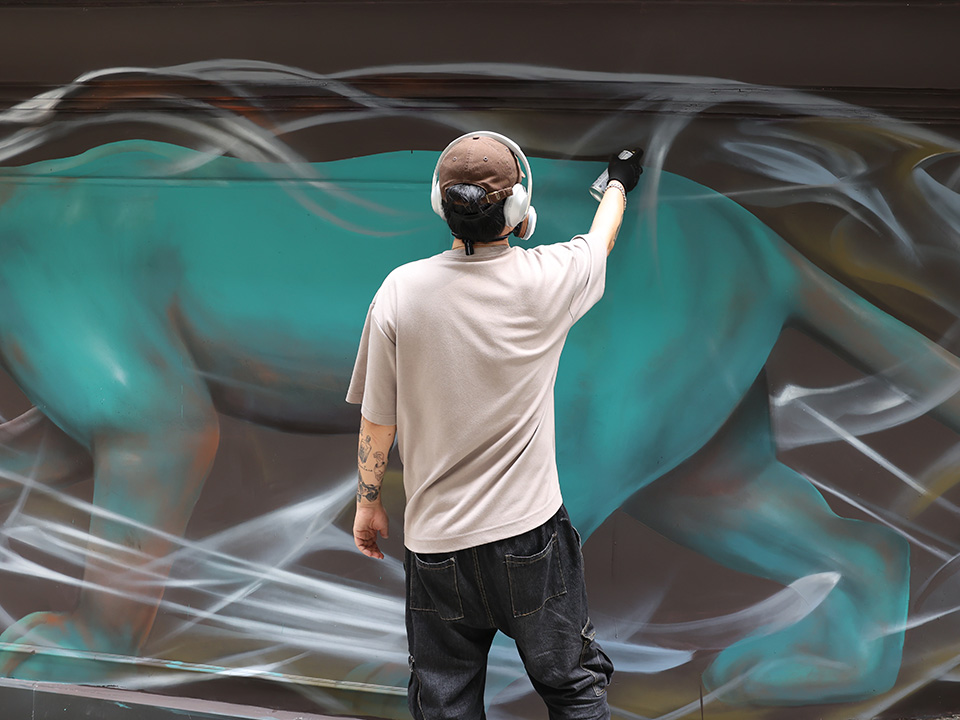 Artist spraying graffiti on wall during the HKwalls Street Art Festival.