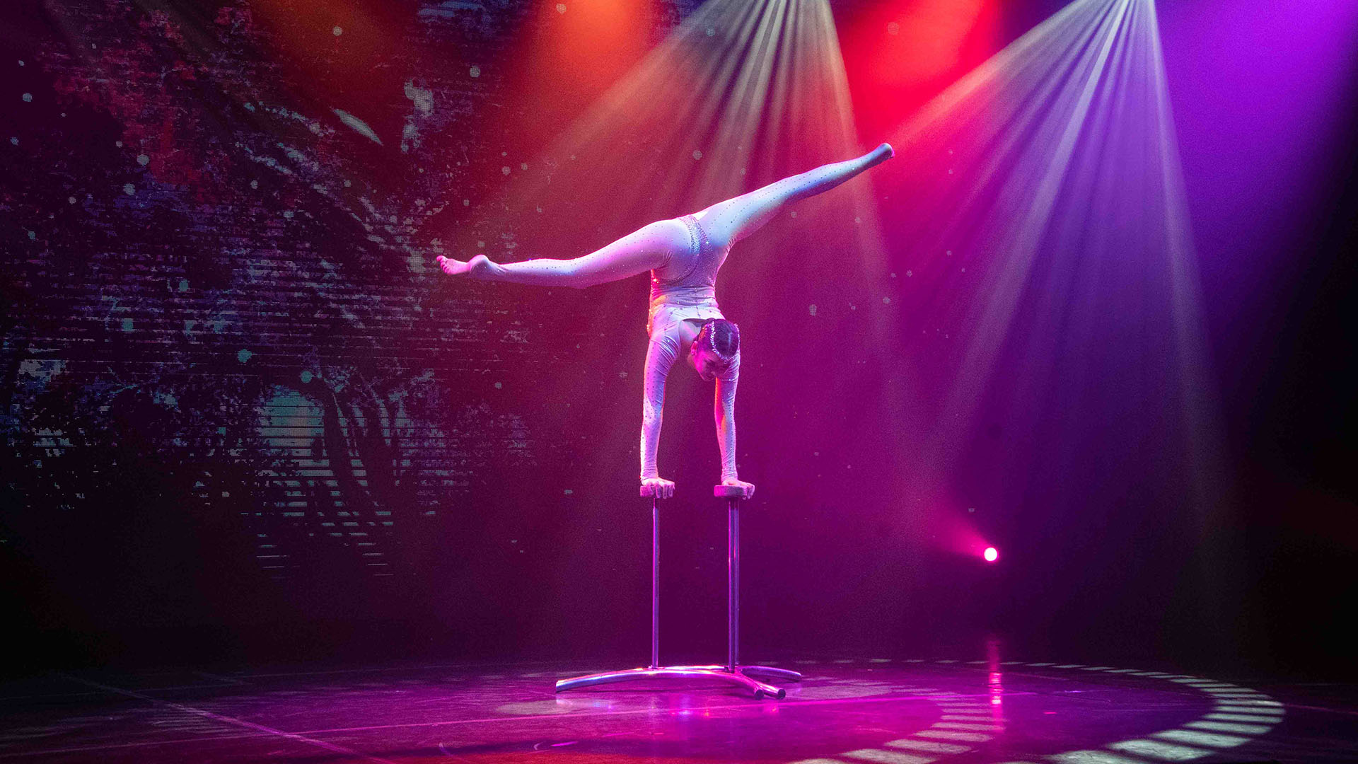 A Star Voyager performer balancing on a stage under colourful lights. 