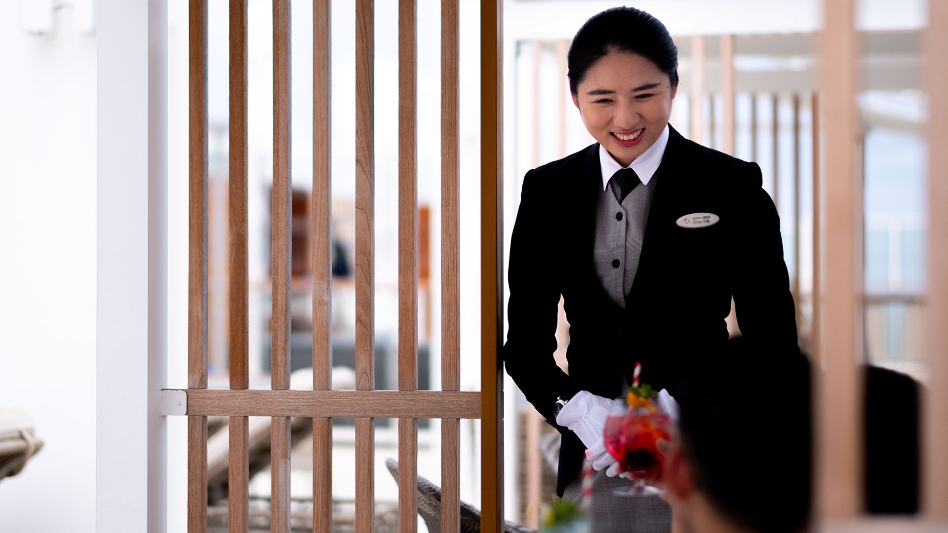 Staff in a suit smiling at a guest on the Star Voyager cruise.