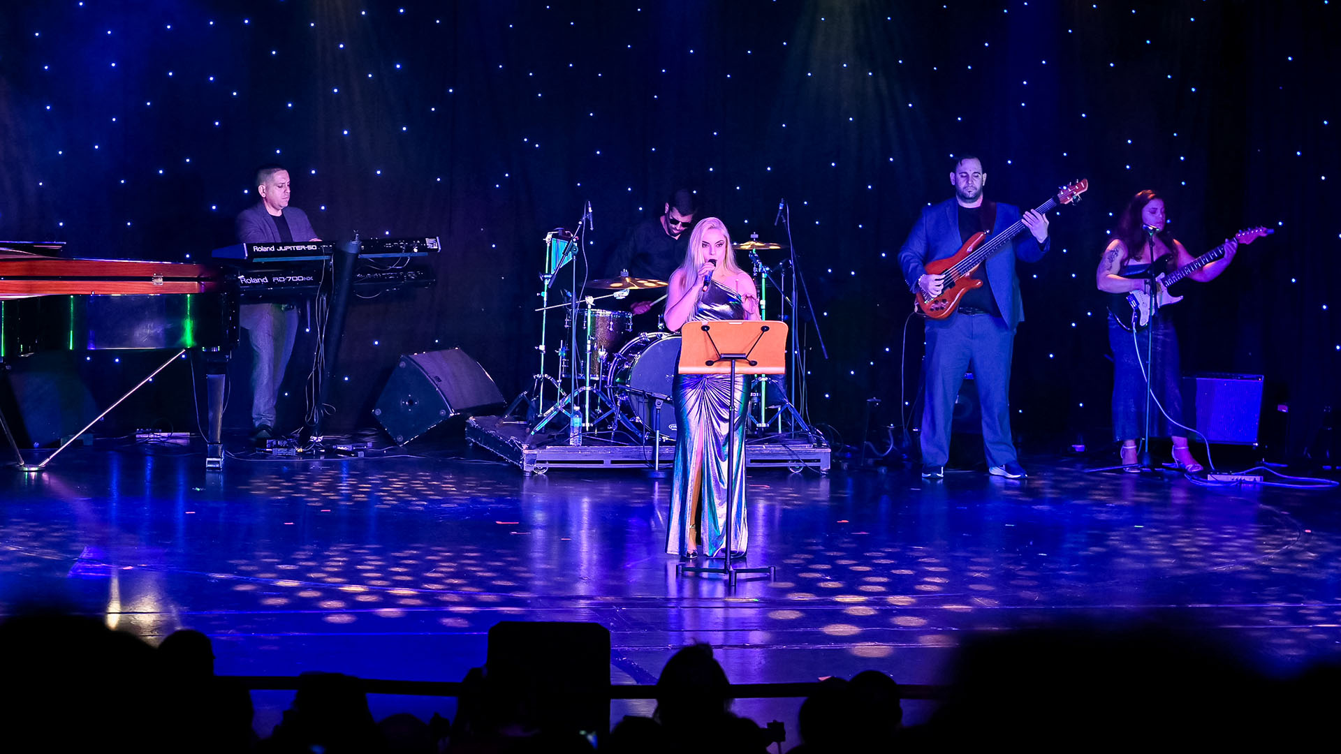 A singer on stage with a live band.