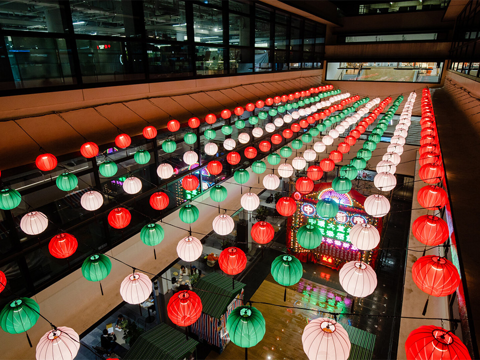 Large vibrant display of red, green and white lanterns at Central Market in Hong Kong at night.