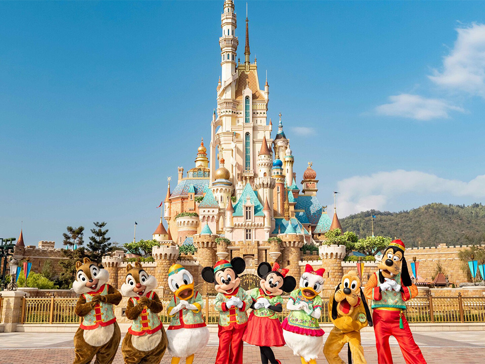 Disney characters dressed in festive Chinese attire greeting everyone outside the Hong Kong Disneyland castle.