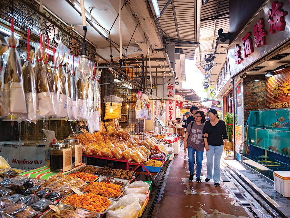 ถนนที่เต็มไปด้วยแผงขายอาหารทะเลตากแห้งและร้านอาหารทะเล