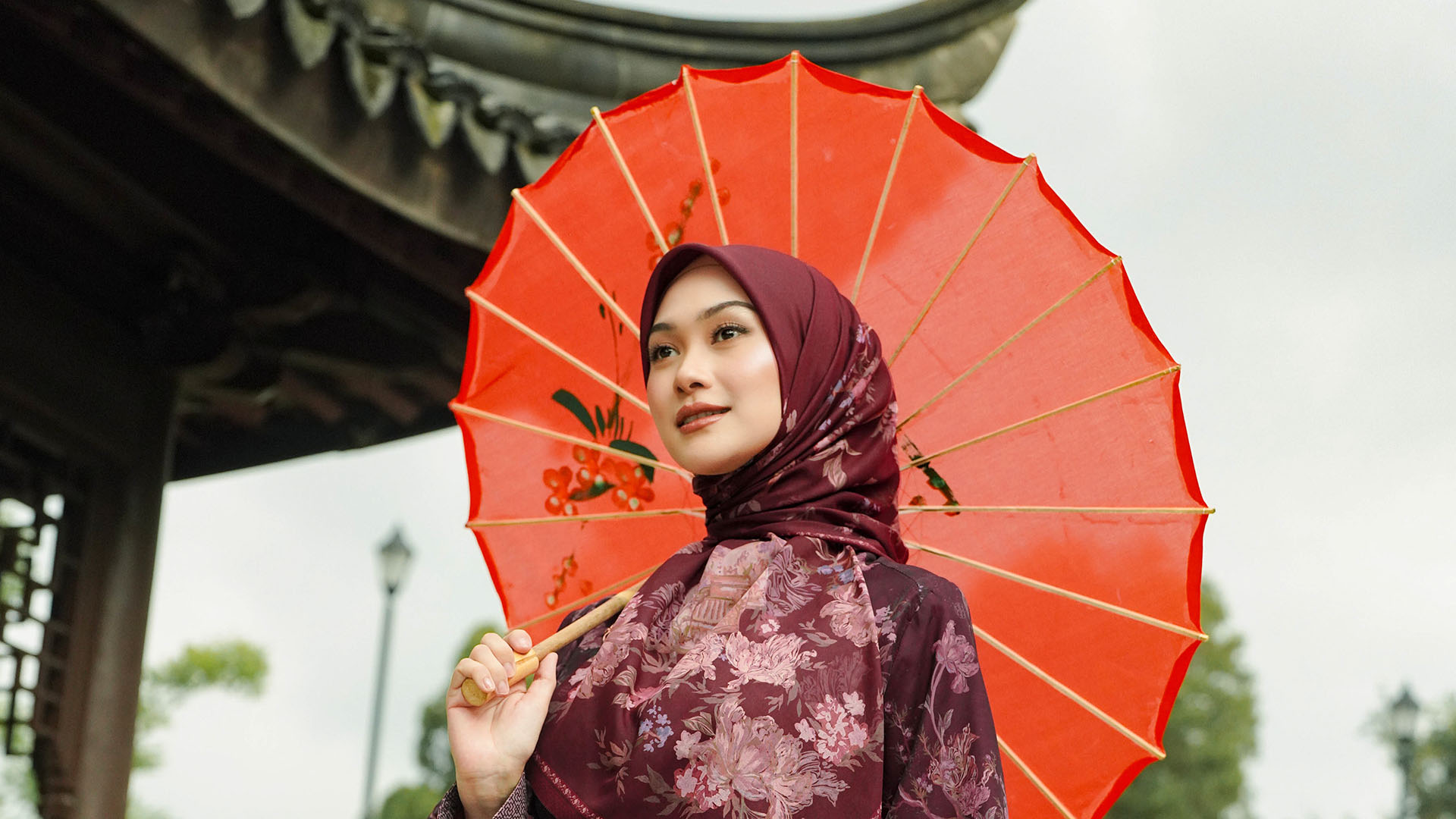 Indah Nada Puspita in a red outfit holding a red umbrella.