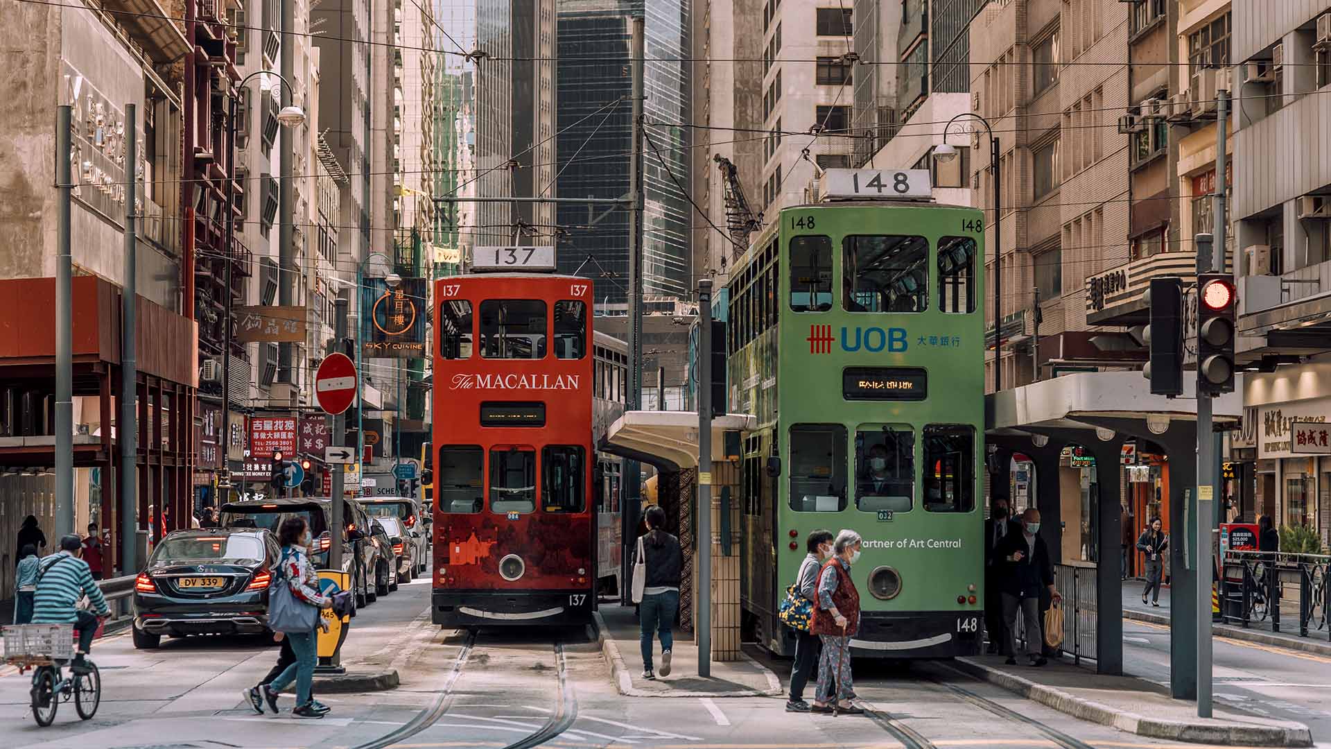 A red and green tram through the streets of Hong Kong.
