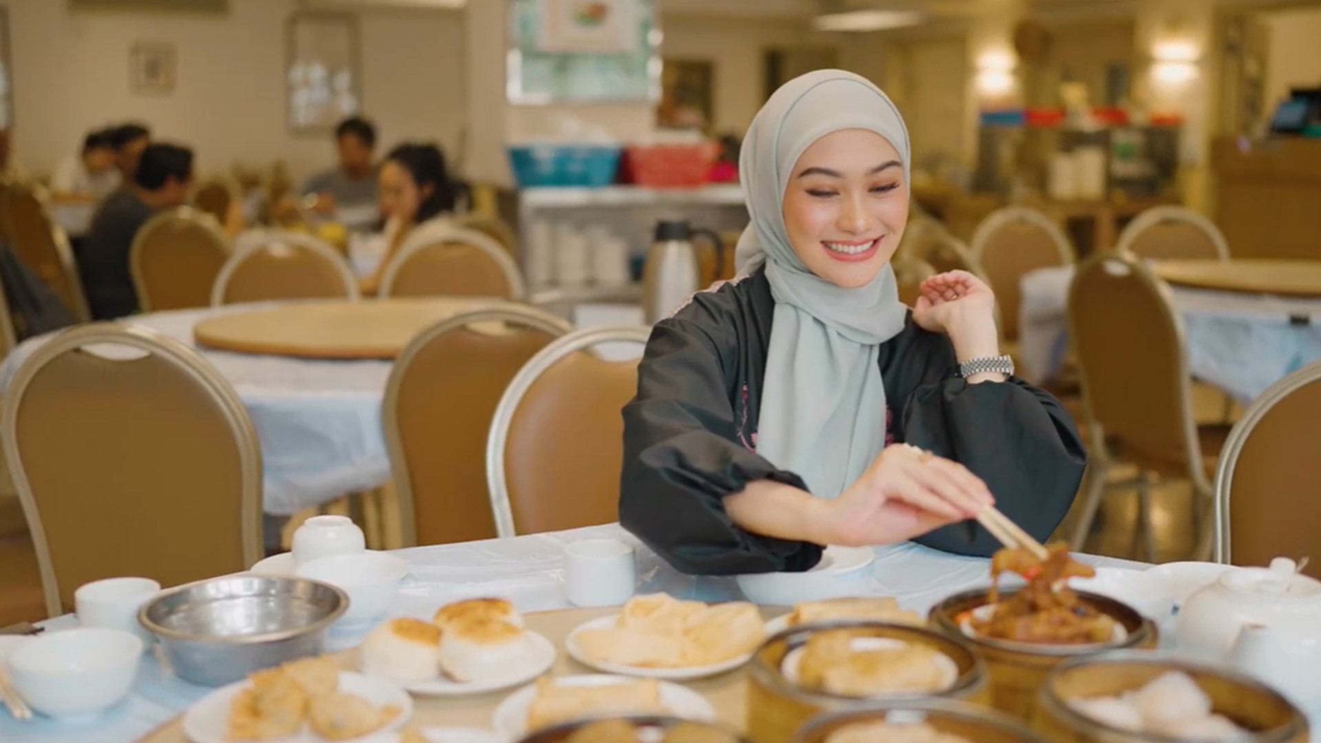 Indah Nada Puspita picking up some dim sum with chopsticks to eat.