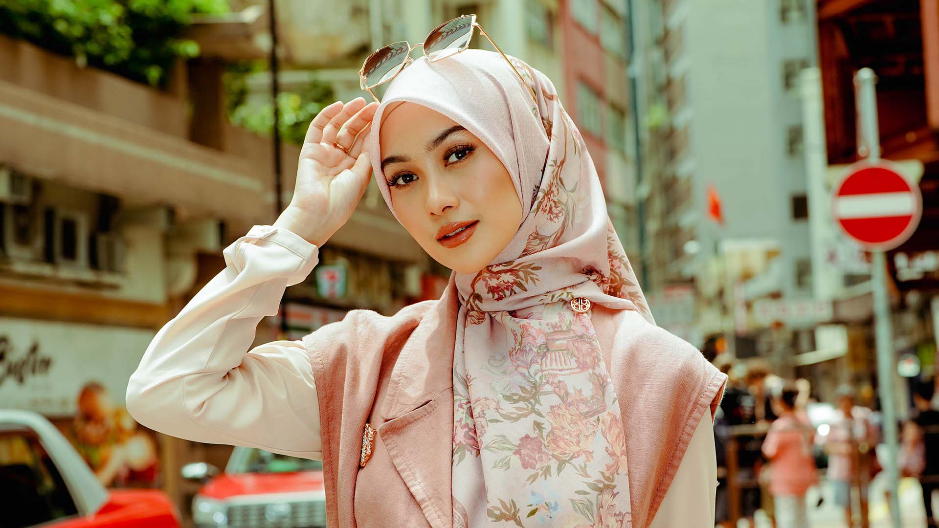 Indah Nada Puspita dressed in pink with red taxis behind her in Hong Kong.