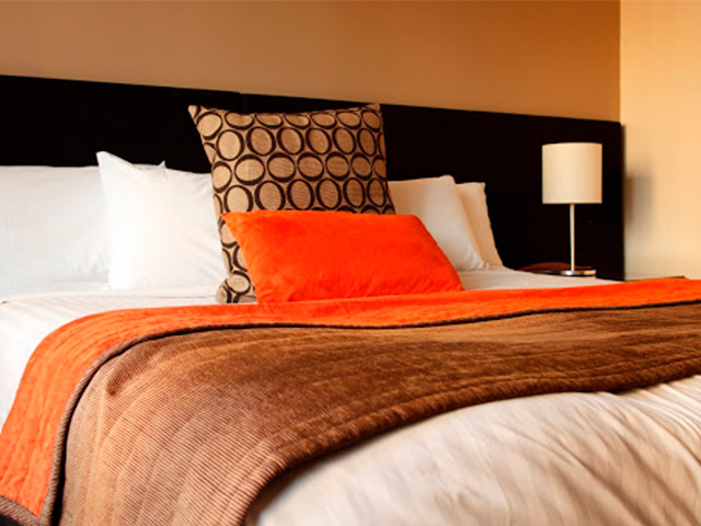 A neatly made up guesthouse bed with bedside lamp