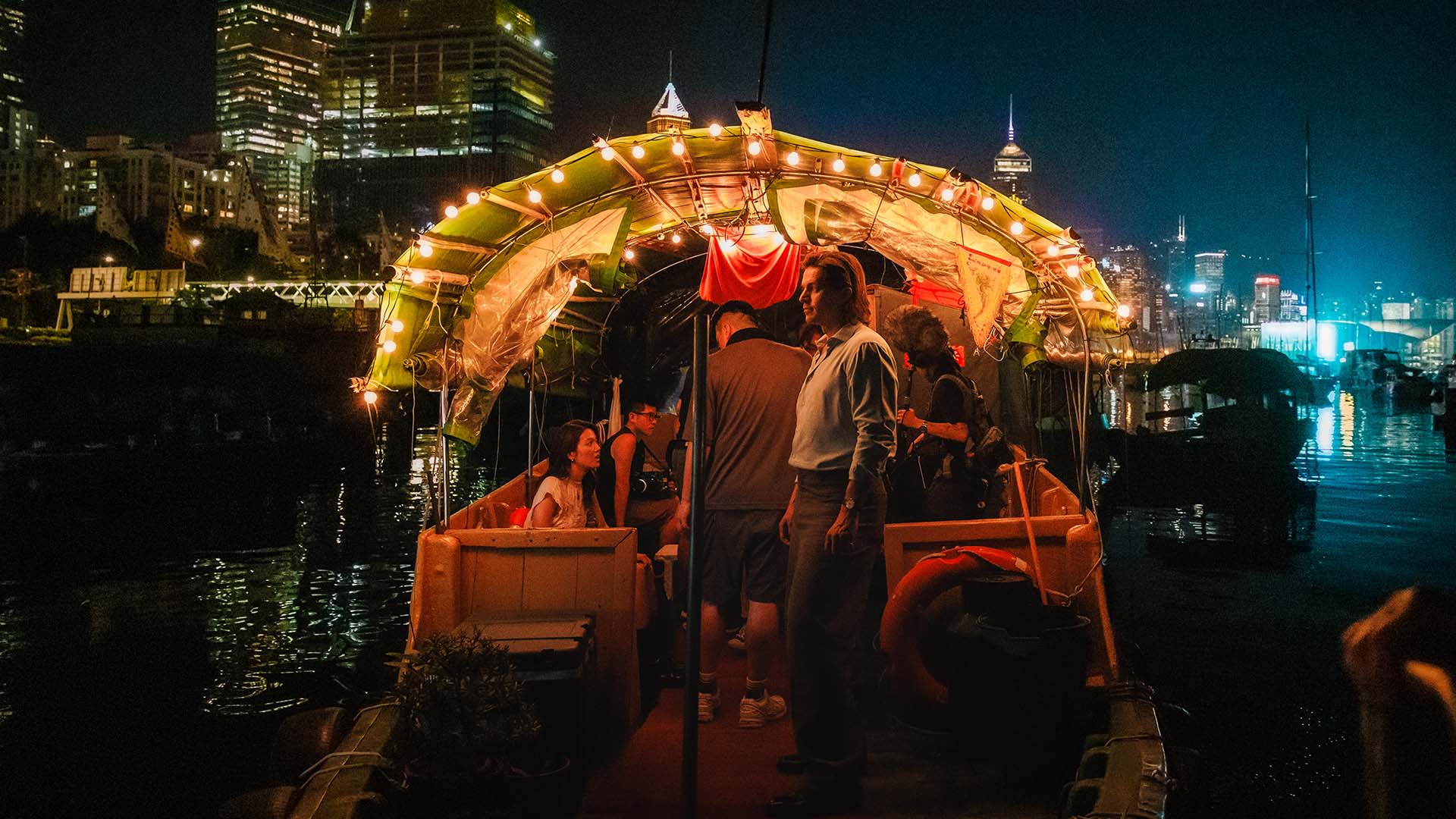 Lucas Bravo aboard a sampan in Hong Kong at night.